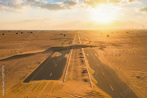 Aerial view of half desert road or street with sand dune in Dubai City, United Arab Emirates or UAE. Natural landscape background at sunset time. Famous tourist attraction. Top view.
