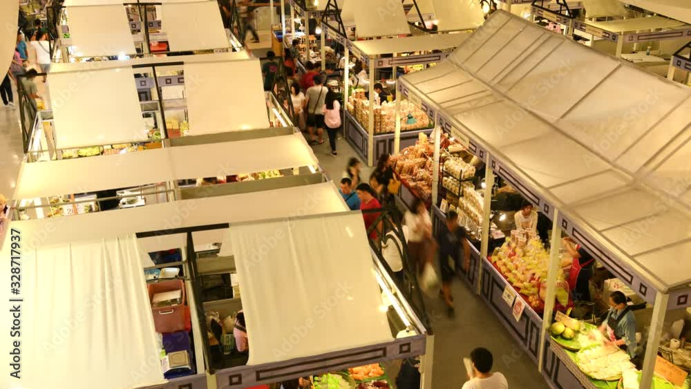 Time lapse of crowd walking and buying goods in the market stall .