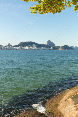 Trees and sunny day on vacation trip to the end of Copacabana beach in Guanabara Bay and in the background the Pao de Acucar mountain  in Rio de Janeiro Brazil