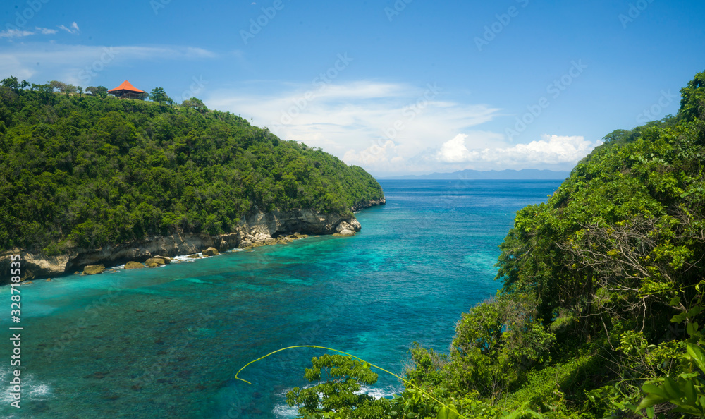 wide scenic view at tropical paradise island of Bali of turquoise sea and cliffs in the horizon under a blue sky in Summer holidays travel destination concept wide scenic view at tropical paradise island of Bali of turquoise sea and cliffs in the horizon under a blue sky in Summer holidays travel destination concept