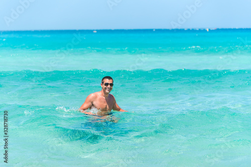 Attractive young caucasian man in the sea , wearing glasses. Summer vacation concept. © miladrumeva