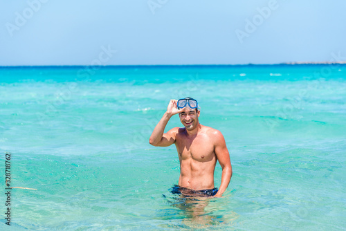 Attractive young caucasian man in the sea , wearing glasses. Summer vacation concept.