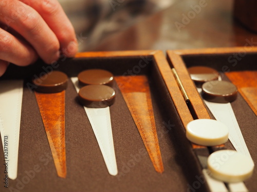 Photo Backgammon Board with Man's Hand Moving Pieces