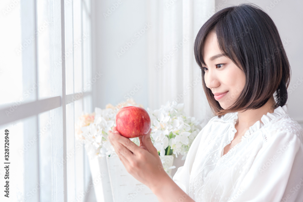 Beautiful Asian girl with apple in house,  education or health or startup business concept, modern office or living room with copy space