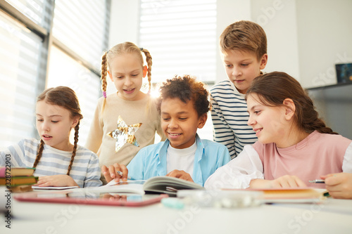 Fotografi Group of curious middle schoolers spending break time together in classroom look