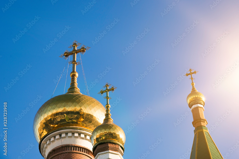Three domes of the Orthodox Church against the blue sky in the sun. Religious architecture