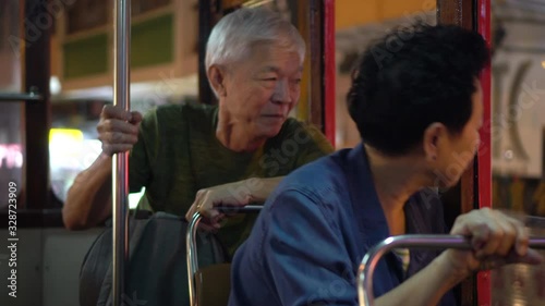 Asian elder couple have fun travel in Hong Kong tram at night photo