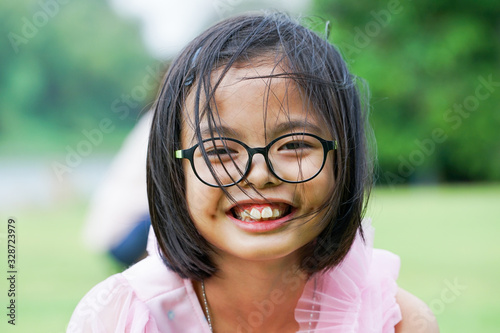 Closeup smiling face of Asian girl looking at the camera with blurred natural background