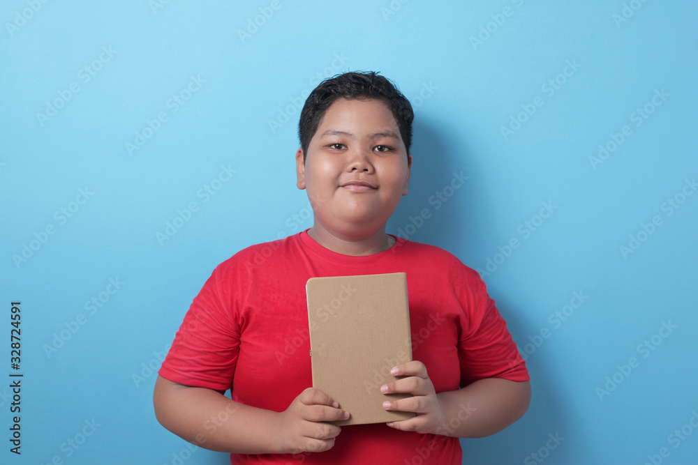 Obraz premium Asian student boy holding book and smile to camera, educational and knowledge concept