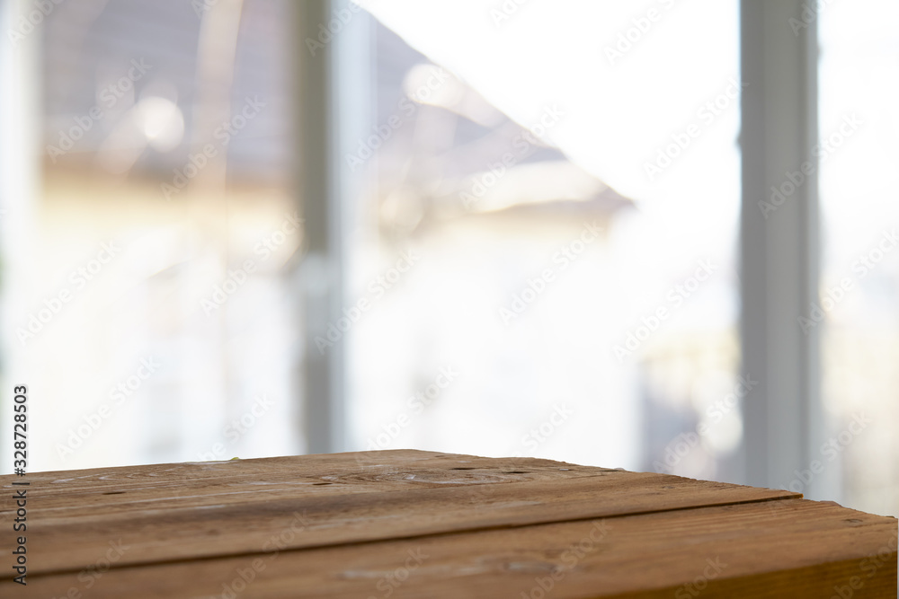 An empty wooden tabletop on a window pane and abstract green blur from the garden with a view of the yard, can be used to display or assemble your products (or products).