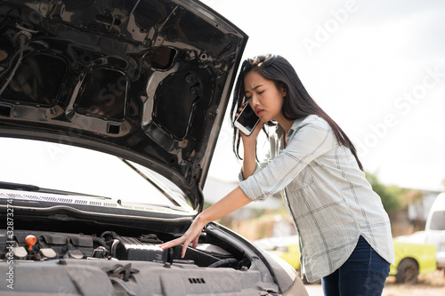 Asian young woman are stressed and calling car insurance.Broken down car while traveling.Black long hair woman talking on cellphone after car breakdown trouble problem mechanic.