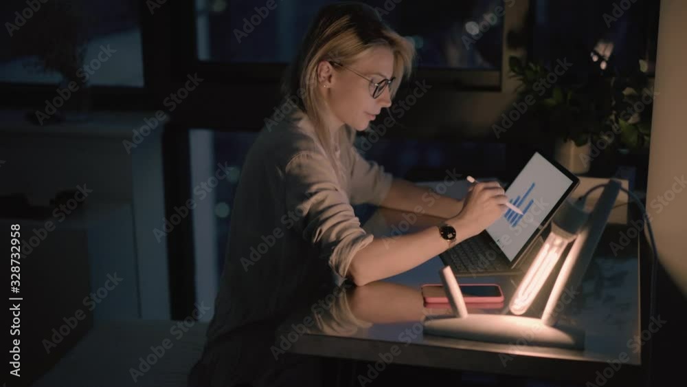 Caucasian financial expert with electronic stylus drawing statistic graphics during overtime distance job, young smart casual analyst browsing market application for creating web diagrams