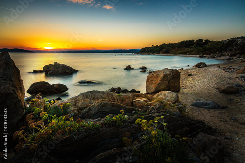 beautiful sunrise or sunset over the greek sea. beautifully photographed along the coast with stones and plants as foreground