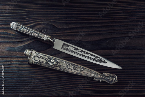 Dagger and scabbard on the black wood photo