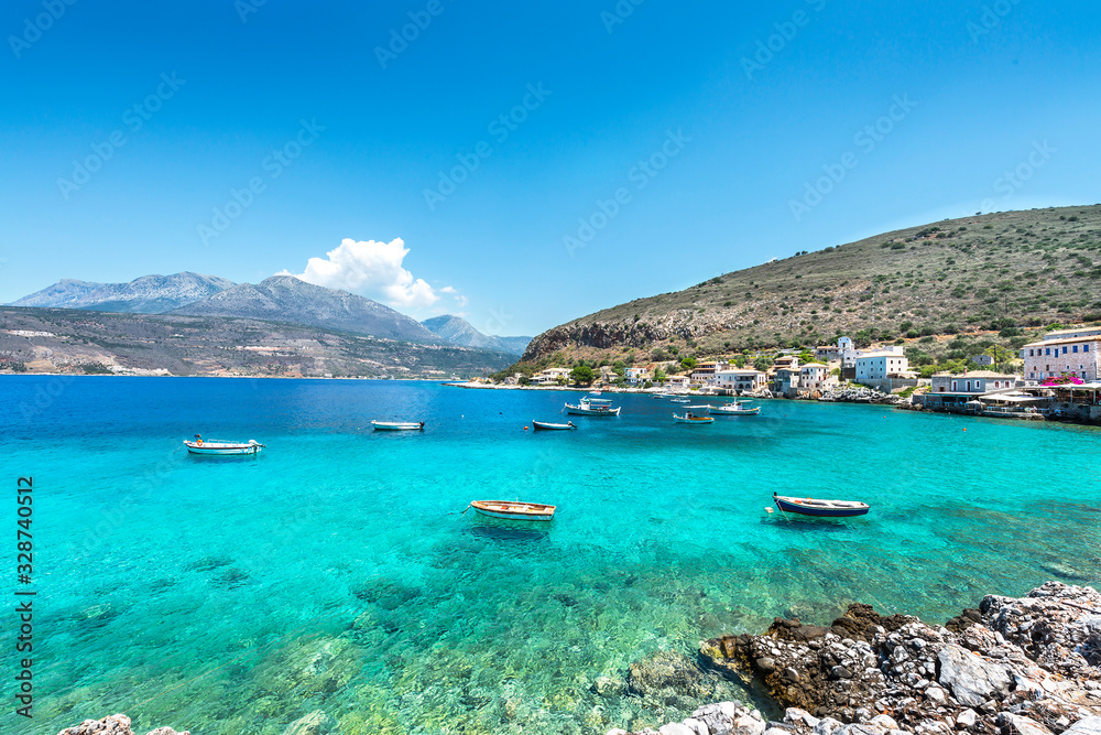 Small fishing boats on turqoise water of meditteranean bay. Landscape image of Greek sea village.