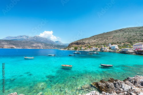 Small fishing boats on turqoise water of meditteranean bay. Landscape image of Greek sea village.