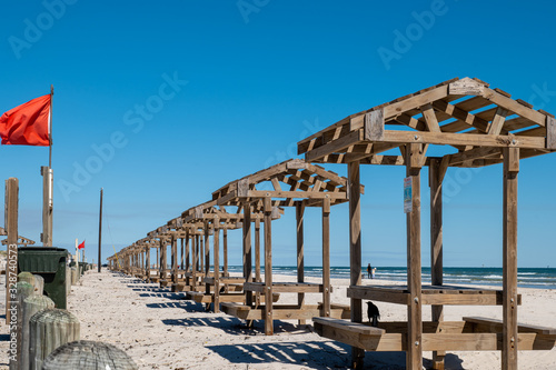 Row of wooden picnic tables with pergola tops at a Gulf of Mexico public beach on North Padre Island, Texas on a sunny day. photo