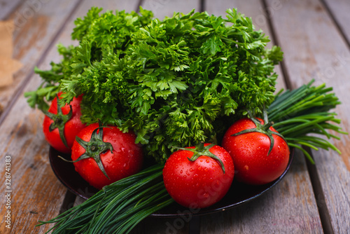 Fresh bright vegetables and herbs on a wooden table.