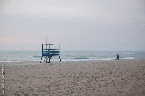 rescue tower on the empty beach one unrecognizable man walk along the beach