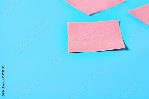 Scattered pink square blank paper stickers on blue background. Copy space