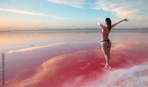 Sexy girl in a black and red swimsuit on the background of the salt lake at amazing sunset
