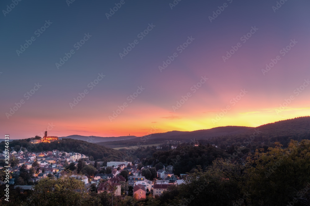 Beautiful sunset over a valley with a village and a ruined castle.  in the middle of the forest with lots of nature and great sun rays in the sky