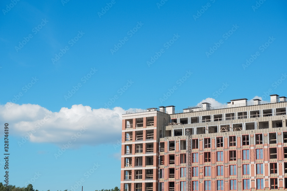 New building construction. construction of an apartment building against blue sky. new luxury district of town. promising development of the city . Facing the building with bricks