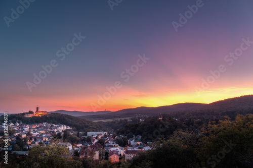 Beautiful sunset over a valley with a village and a ruined castle.  in the middle of the forest with lots of nature and great sun rays in the sky © Jan
