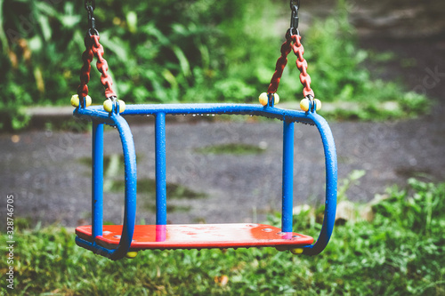 Wet swing on playground. Rainy summer weather_