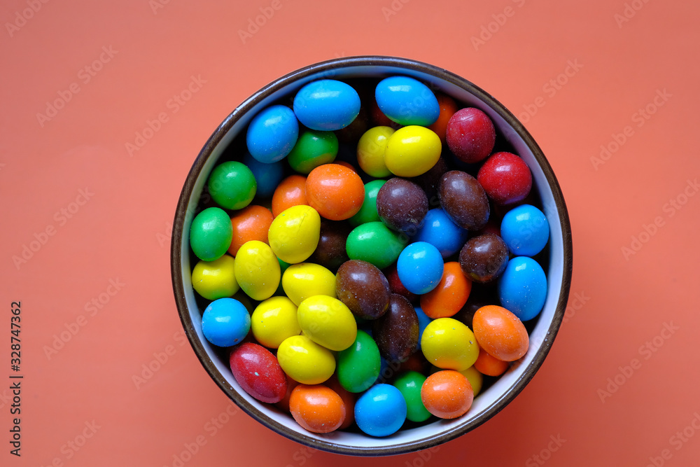 colorful chocolate candy in a bowl on range background