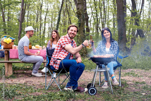 Group of young people making barbecue and having picnic in nature
