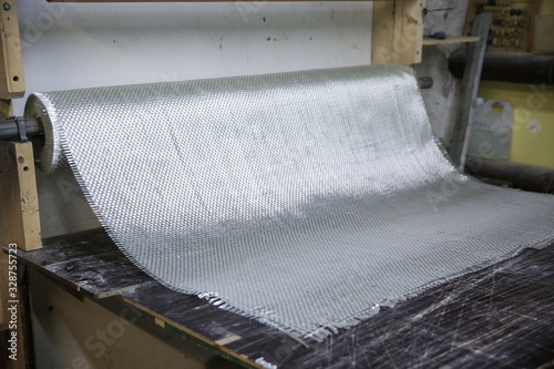 roll of fiberglass fabric is on the working table in workshop photo