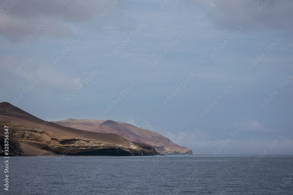 islands, sand-colored rocks and the sea with a blue sky and white clouds