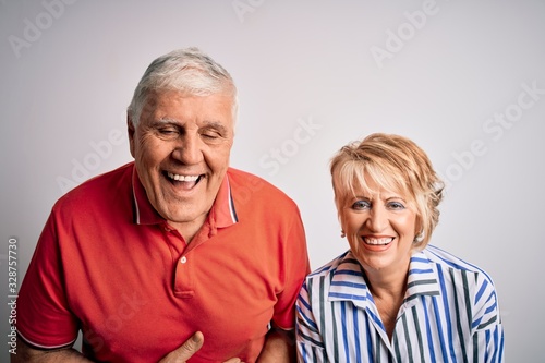 Senior beautiful couple standing together over isolated white background smiling and laughing hard out loud because funny crazy joke with hands on body.