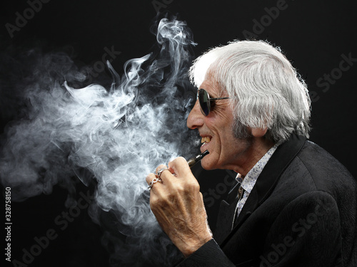 Elderly cool male character enjoying vaping, smoke swirling on black background
