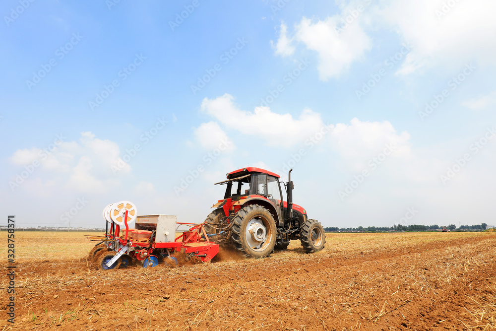 Obraz premium Farmers drive farm machinery to plant corn on the farm, Luannan County, Hebei Province, China.