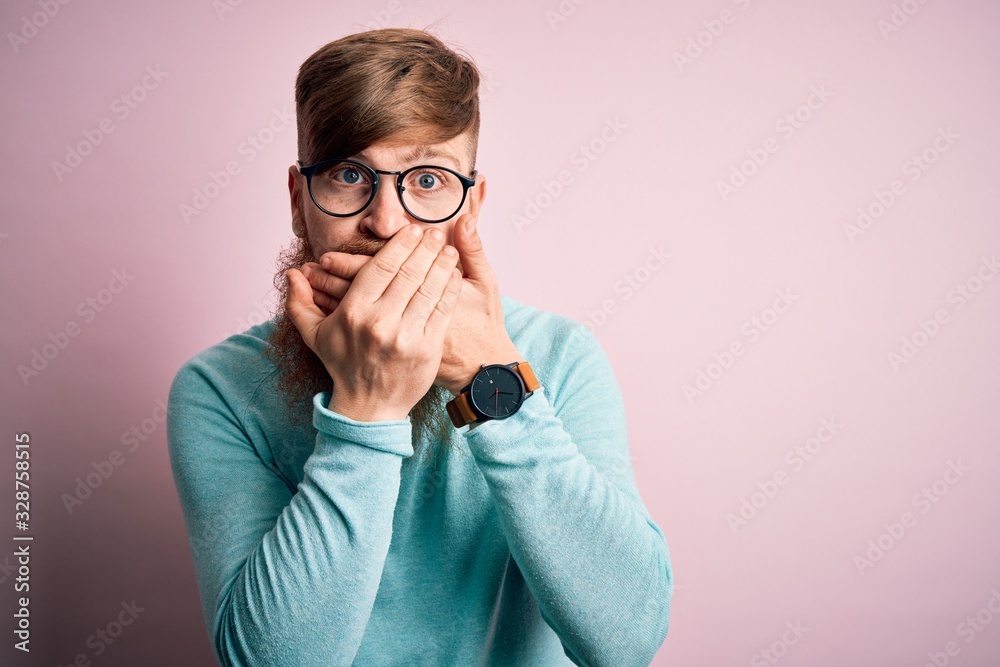Handsome Irish redhead man with beard wearing glasses over pink isolated background shocked covering mouth with hands for mistake. Secret concept. Handsome Irish redhead man with beard wearing glasses over pink isolated background shocked covering mouth with hands for mistake. Secret concept.