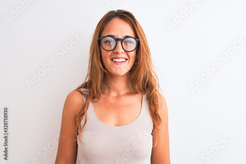 Young redhead woman wearing glasses standing over white isolated background with a happy and cool smile on face. Lucky person.