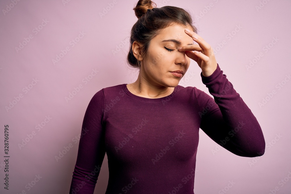 Beautiful young woman wearing casual bun hairstyle over pink isolated background tired rubbing nose and eyes feeling fatigue and headache. Stress and frustration concept. Beautiful young woman wearing casual bun hairstyle over pink isolated background tired rubbing nose and eyes feeling fatigue and headache. Stress and frustration concept.