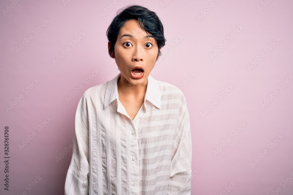 Young beautiful asian girl wearing casual shirt standing over isolated pink background afraid and shocked with surprise and amazed expression, fear and excited face. Young beautiful asian girl wearing casual shirt standing over isolated pink background afraid and shocked with surprise and amazed expression, fear and excited face.