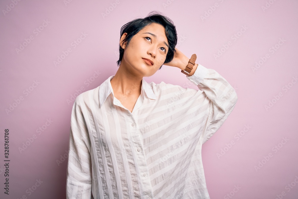 Young beautiful asian girl wearing casual shirt standing over isolated pink background confuse and wondering about question. Uncertain with doubt, thinking with hand on head. Pensive concept. Young beautiful asian girl wearing casual shirt standing over isolated pink background confuse and wondering about question. Uncertain with doubt, thinking with hand on head. Pensive concept.