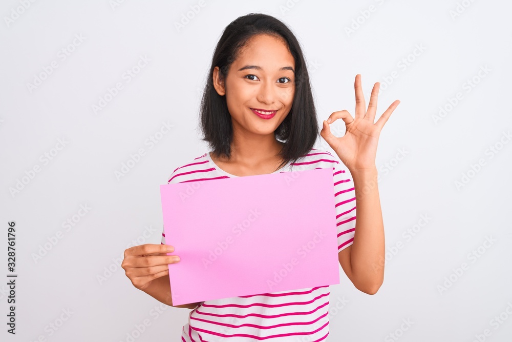 Young beautiful chinese woman holding banner standing over isolated white background doing ok sign with fingers, excellent symbol Young beautiful chinese woman holding banner standing over isolated white background doing ok sign with fingers, excellent symbol