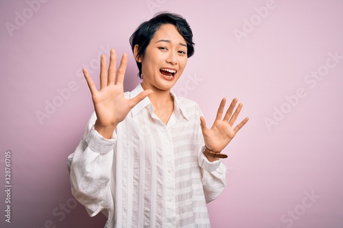 Young beautiful asian girl wearing casual shirt standing over isolated pink background afraid and terrified with fear expression stop gesture with hands, shouting in shock. Panic concept.