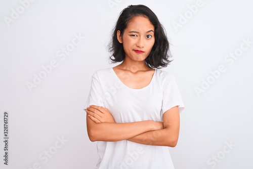 Young chinese woman wearing casual t-shirt standing over isolated white background skeptic and nervous, disapproving expression on face with crossed arms. Negative person.