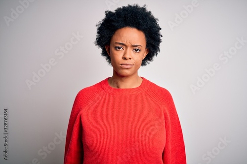 Young beautiful African American afro woman with curly hair wearing red casual sweater looking sleepy and tired, exhausted for fatigue and hangover, lazy eyes in the morning.