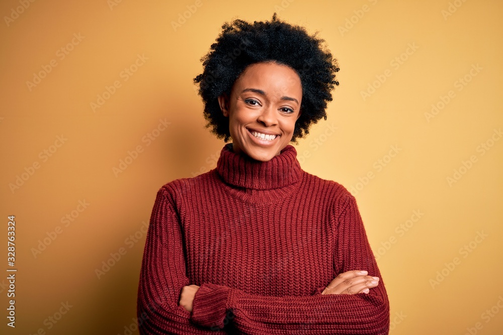Young beautiful African American afro woman with curly hair wearing casual turtleneck sweater happy face smiling with crossed arms looking at the camera. Positive person. Young beautiful African American afro woman with curly hair wearing casual turtleneck sweater happy face smiling with crossed arms looking at the camera. Positive person.