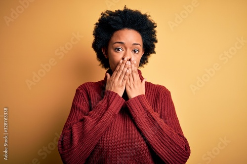 Young beautiful African American afro woman with curly hair wearing casual turtleneck sweater laughing and embarrassed giggle covering mouth with hands  gossip and scandal concept