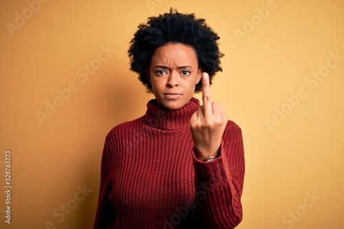 Young beautiful African American afro woman with curly hair wearing casual turtleneck sweater Showing middle finger, impolite and rude fuck off expression