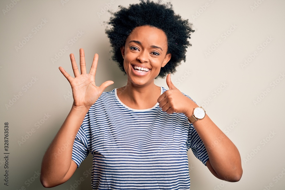 Young beautiful African American afro woman with curly hair wearing striped t-shirt showing and pointing up with fingers number six while smiling confident and happy. Young beautiful African American afro woman with curly hair wearing striped t-shirt showing and pointing up with fingers number six while smiling confident and happy.