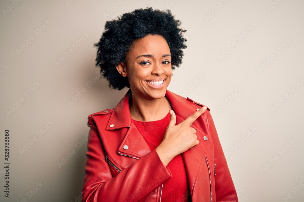 Young beautiful African American afro woman with curly hair wearing casual red jacket cheerful with a smile of face pointing with hand and finger up to the side with happy and natural expression Young beautiful African American afro woman with curly hair wearing casual red jacket cheerful with a smile of face pointing with hand and finger up to the side with happy and natural expression